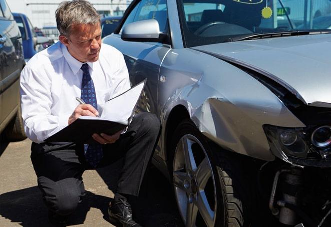 gray car with insurance paperwork and keys on a desk